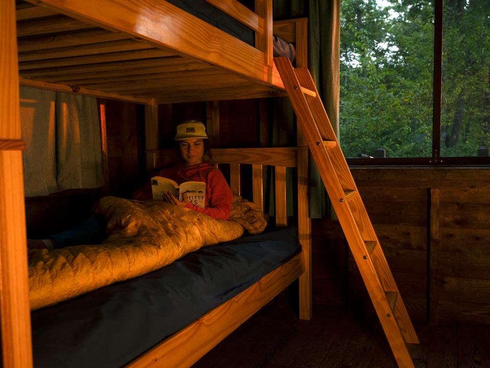 mountain biker woman in cabin reading at bear brook state park