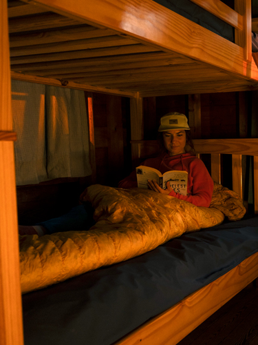 mountain biker woman in cabin reading at bear brook state park
