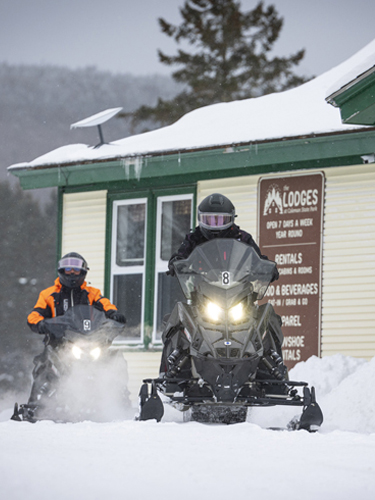 couple snowmobiling at coleman lodges-main lodge
