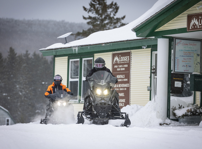 couple snowmobiling at coleman lodges-main lodge