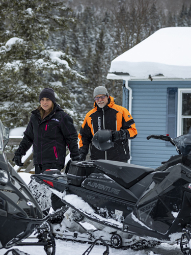couple next to their snowmobiles at coleman lodges