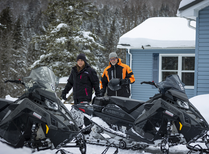 couple next to their snowmobiles at coleman lodges