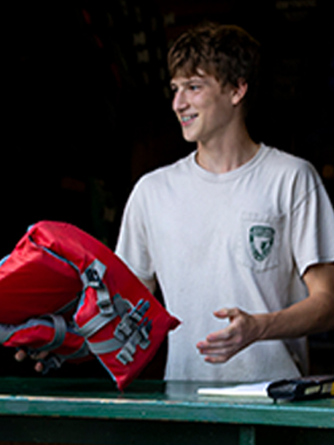 employee with lifejacket rentals at boathouse