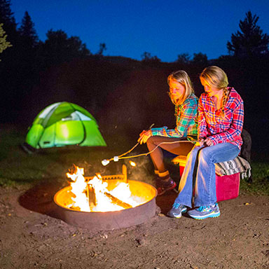 women camping and toasting marshmallows