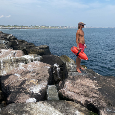 lifeguard on the rocks with rescue float