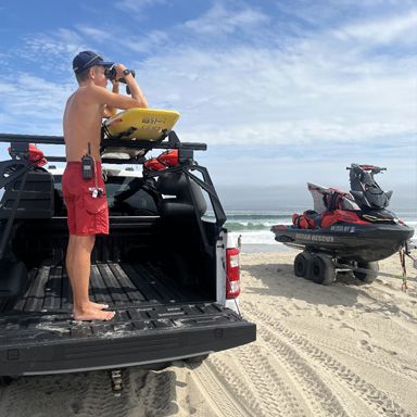 lifeguard with binoculars and rescue vehicle