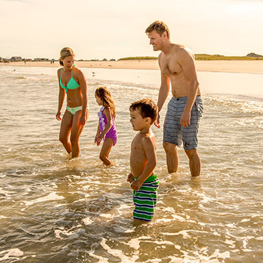 A family walking on the beach at sunset