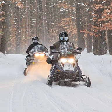 Snowmobiles coming down a trail