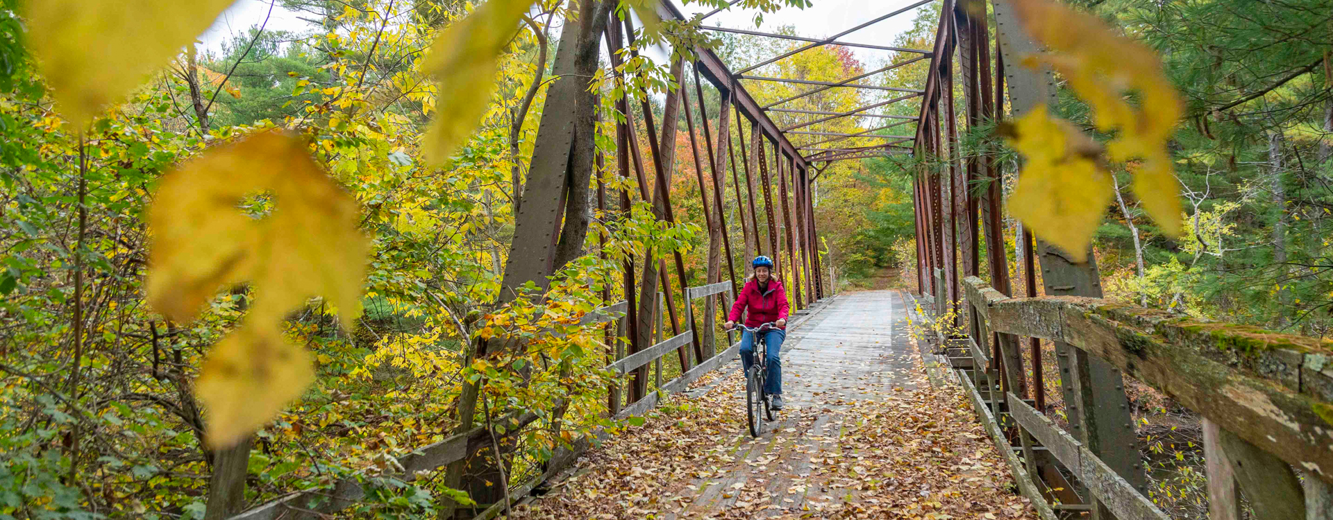 woman biking on ashuelot rail trail bridge