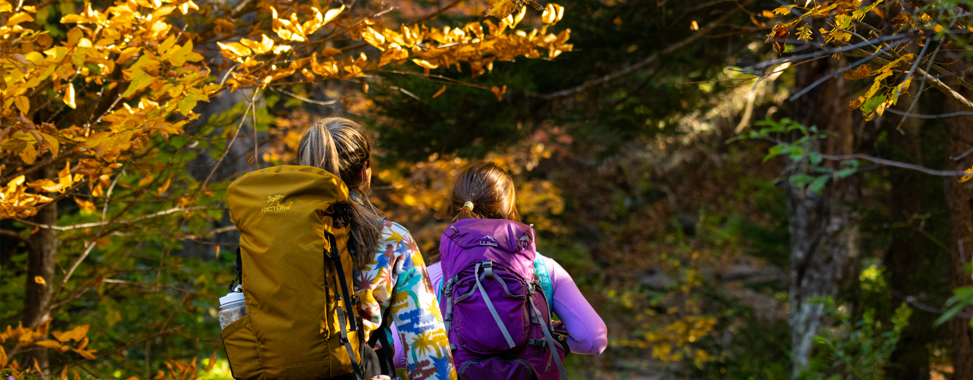 two women hiking in foliage background