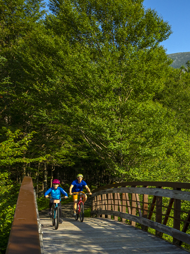 father and son bike riding on the presidential rail trail in franconia notch state park 