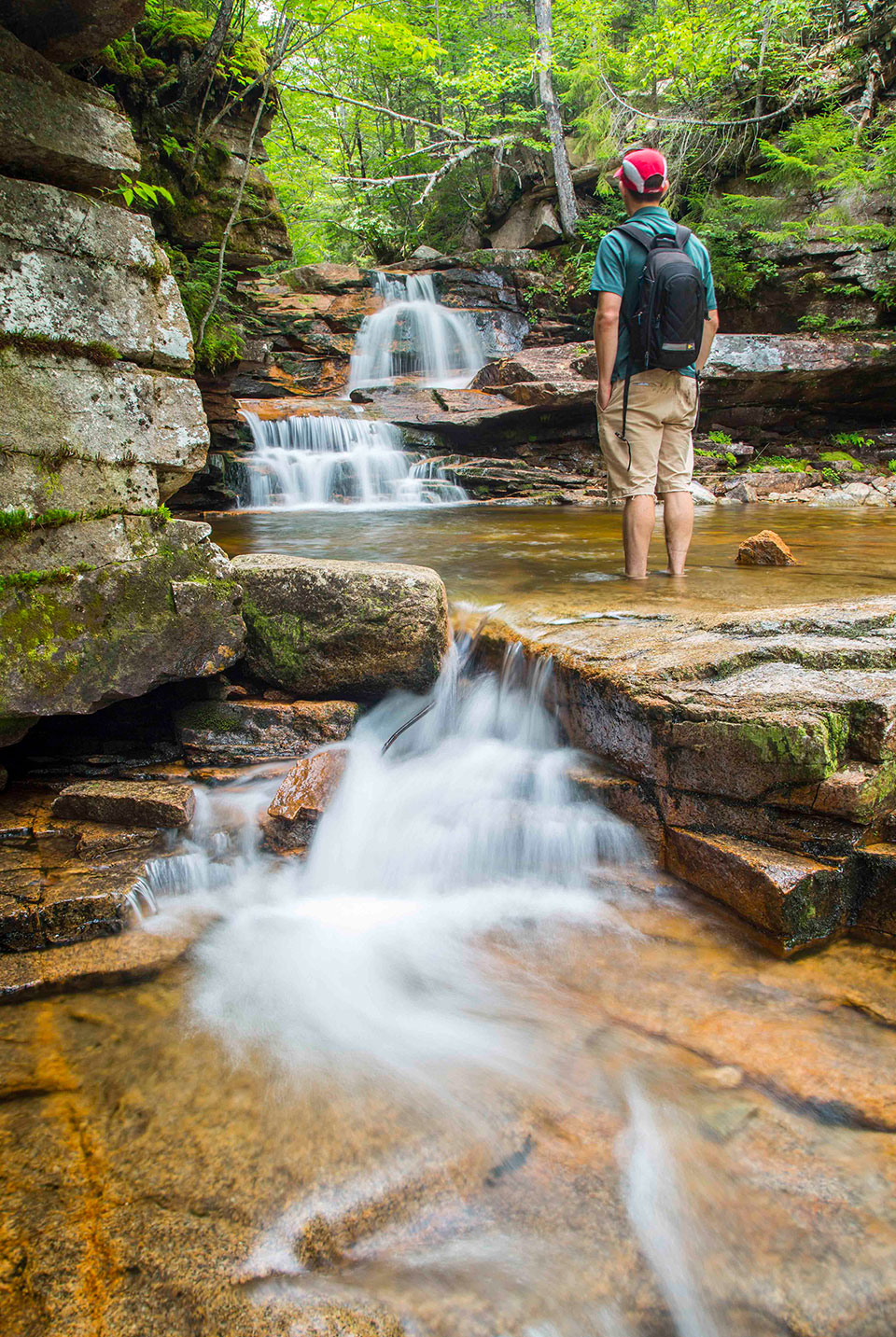 man standing in front of a waterfall at crawford notch