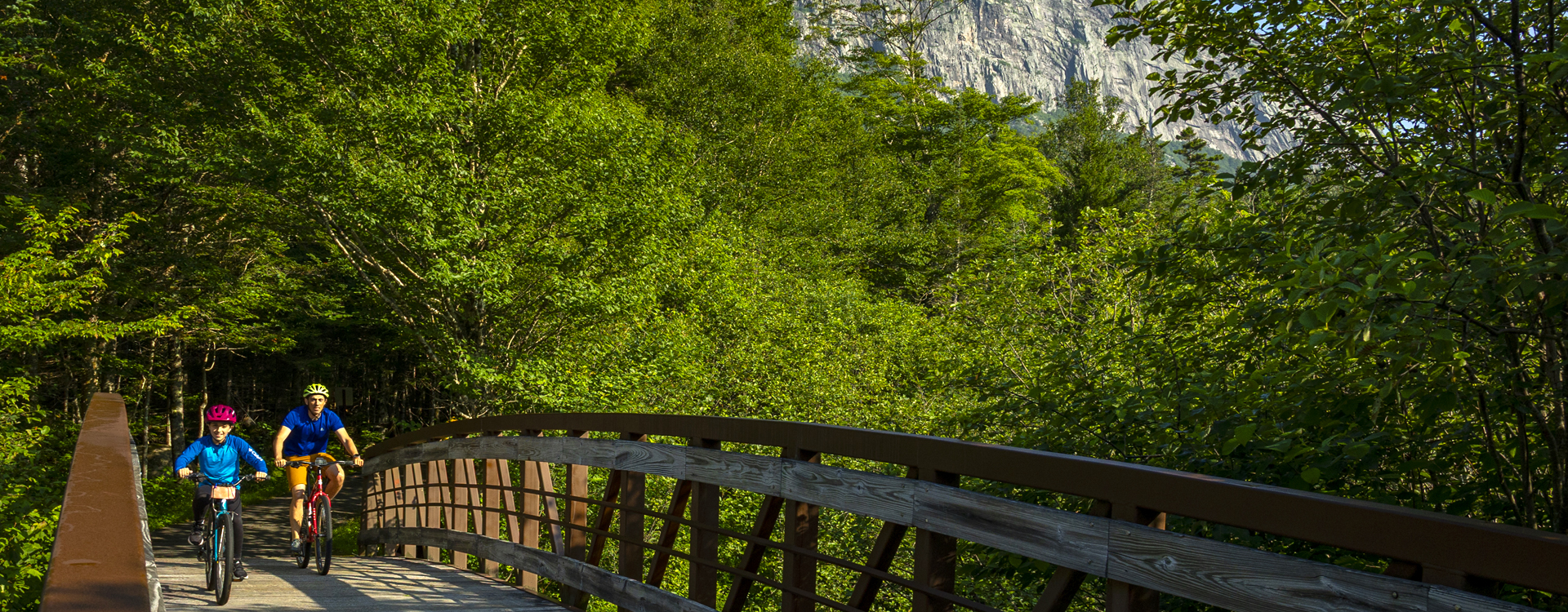 father and son bike riding on the presidential rail trail in franconia notch state park 