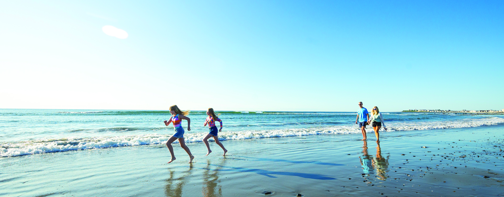 family walking on the beach in water