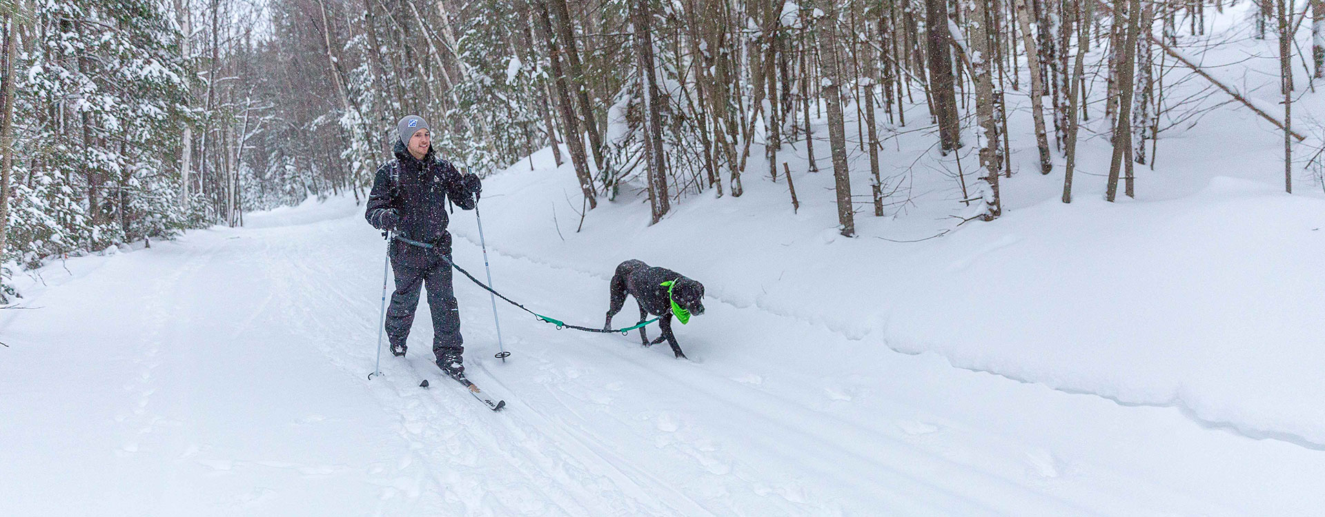 man cross country skiing at Milan hill with his dog