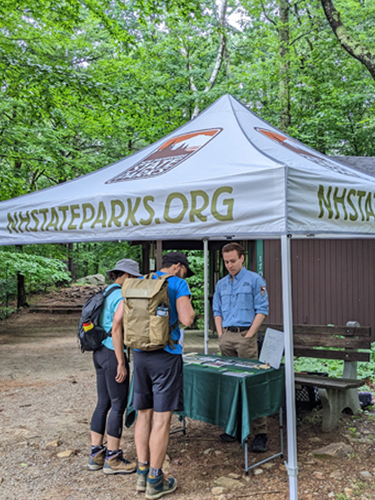 sca ranger under pop-up tent at trailhead with hikers