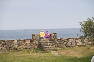 couple sitting on rock wall in front of ocean